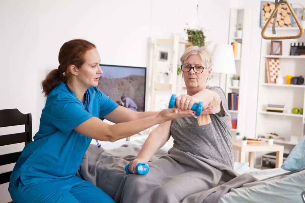 Female doctor helping elderly age woman with physiotherapy